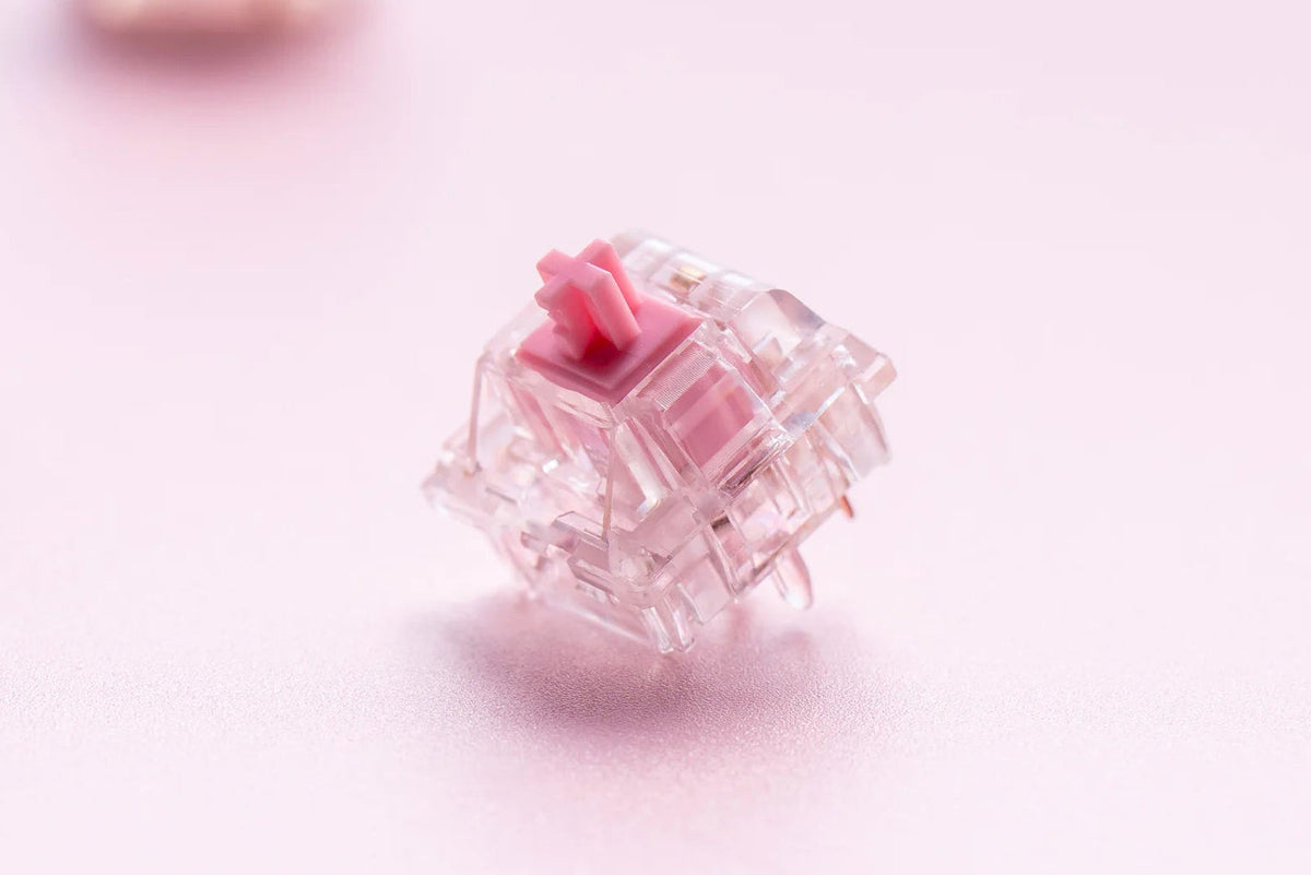 Keygeek Y2X Linear Switch mit rosa Stem und komplett transparentem Gehäuse auf rosa Hintergrund