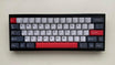 MW Datenshi Keycap Set (Sample) auf einer schwarzen 60%-Tastatur von vorn: Off-White, Dunkelgrau und Rot