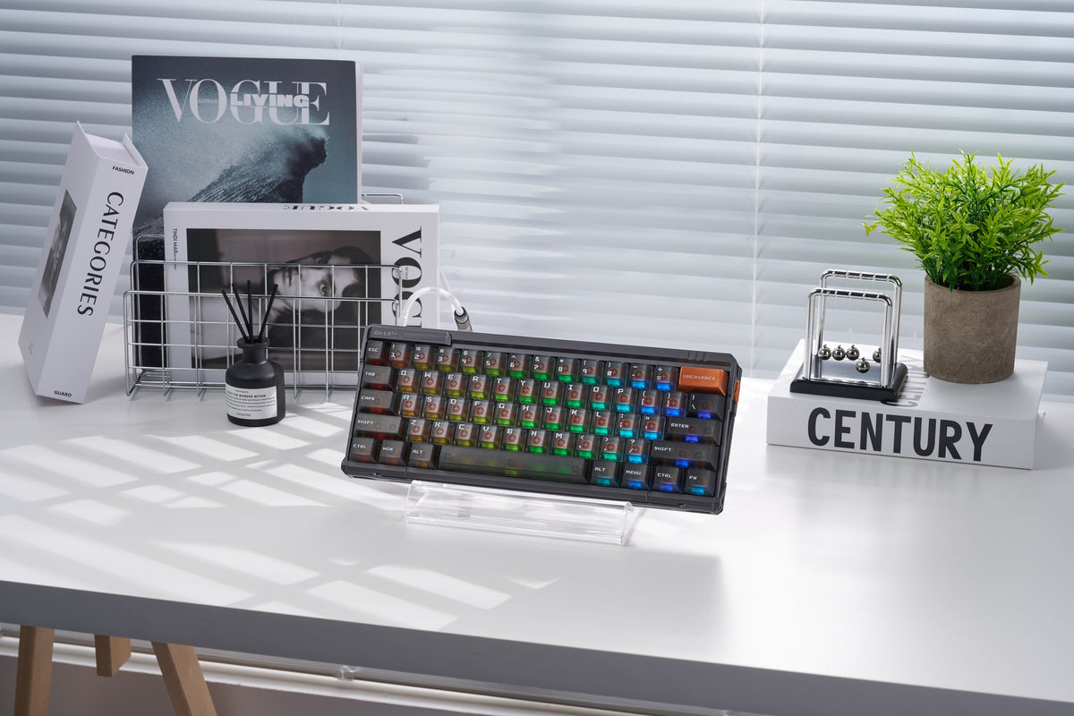 QK60 HE in Meteorite Grey mit bunter RGB-Beleuchtung auf einem Ständer auf einem weißen Schreibtisch