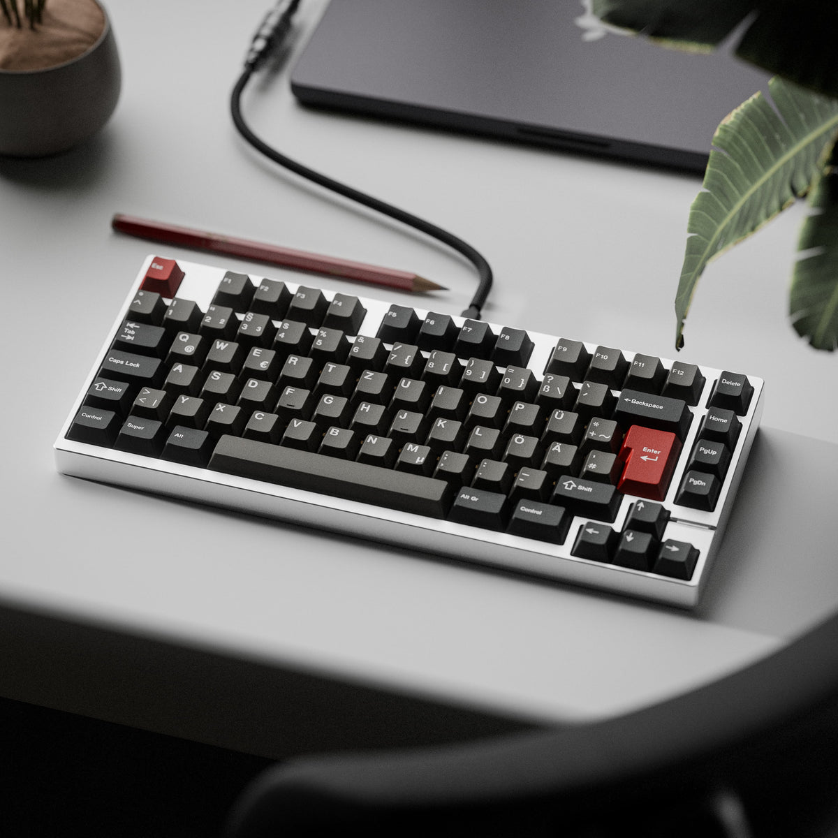KKB Dolch Keycaps in Dunkelgrau mit roten Akzenten auf einer Tastatur neben einer Pflanze