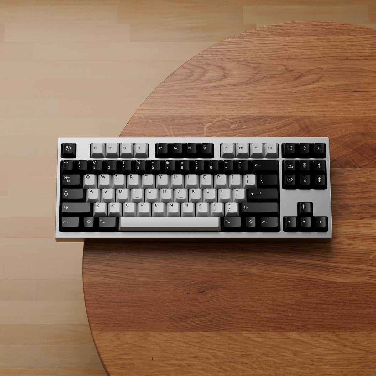 Render: silberne KBDFans Chamber TKL mit schwarzen und weißen Keycaps auf einem runden Holztisch