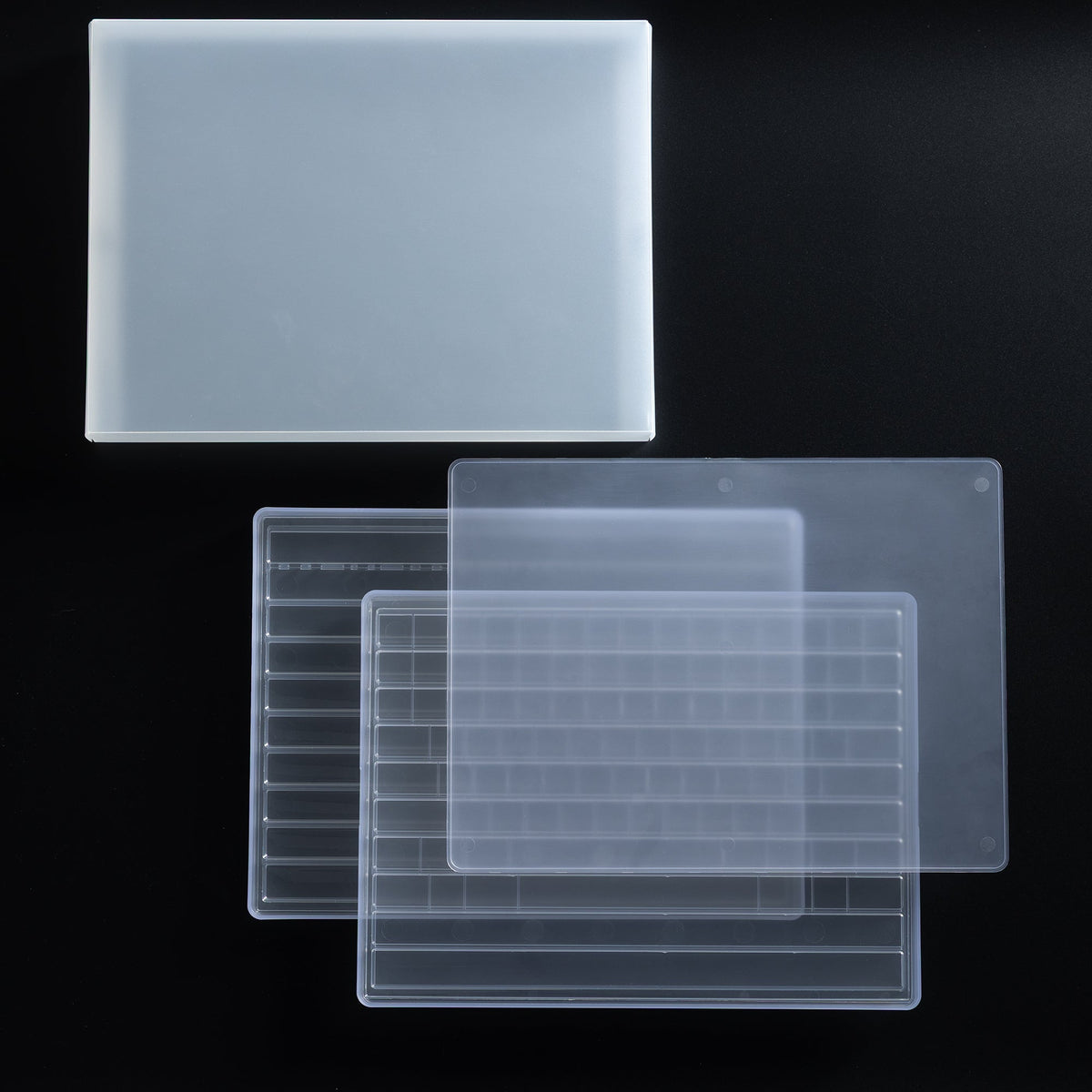 Einzelteile des KBDFans Dual Layer Keycap Trays nebeneinander auf schwarzem Untergrund