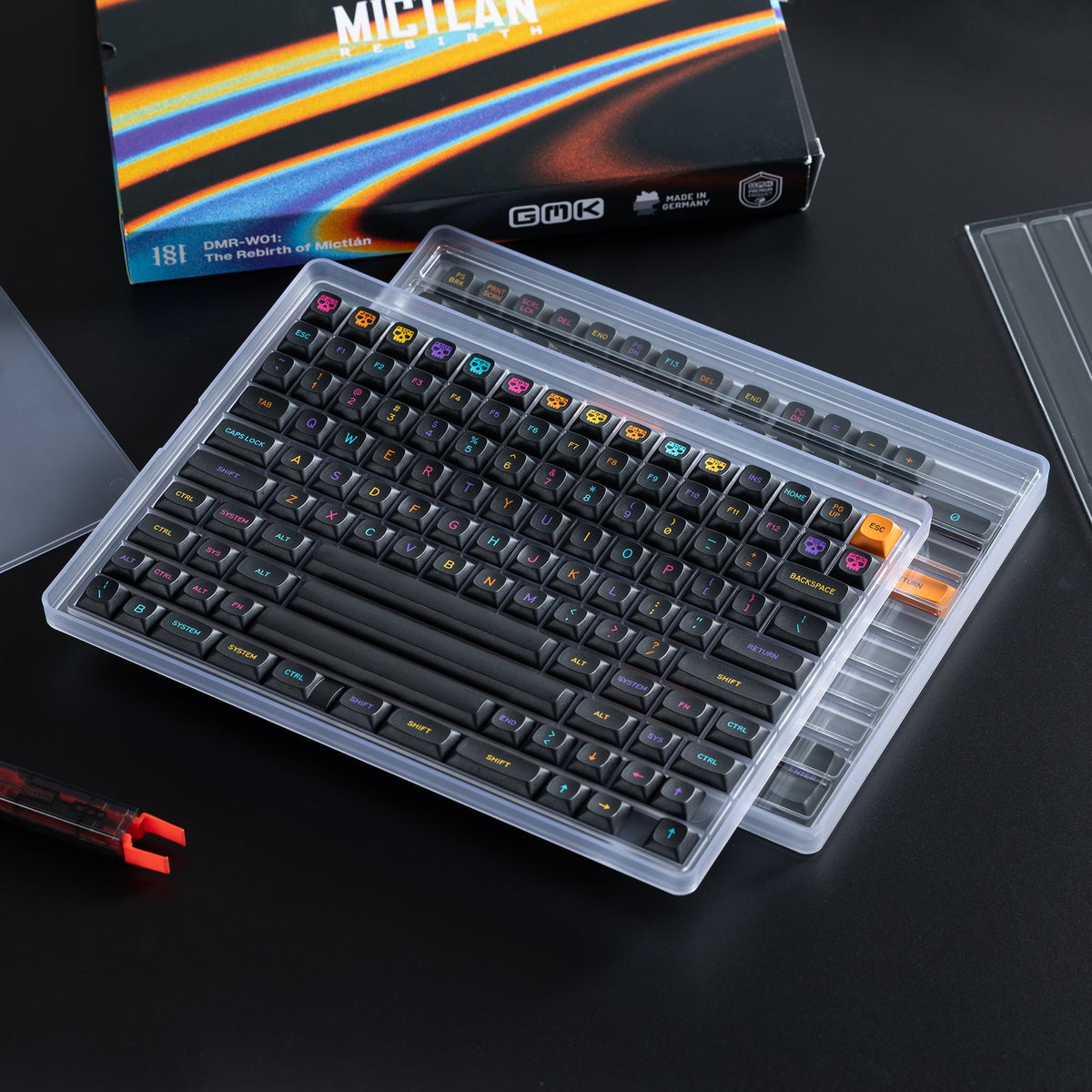 Beide Ebenen des KBDFans Keycap Trays mit schwarzen GMK-Keycaps, dahinter die GMK-Verpackung
