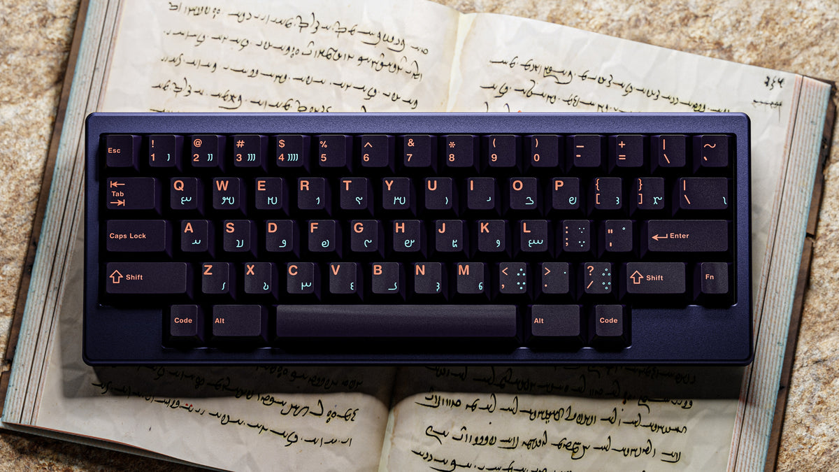 MW Anushirvan Keycaps auf dunkelblauem Case, Draufsicht auf einem aufgeschlagenen alten Buch