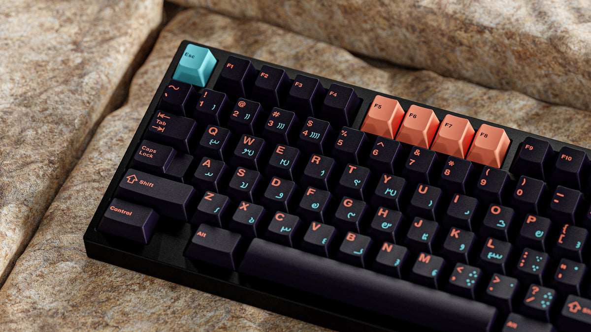 MW Anushirvan Keycaps auf schwarzem Case auf Stein, Nahaufnahme mit türkiser Esc und orangen F-Tasten