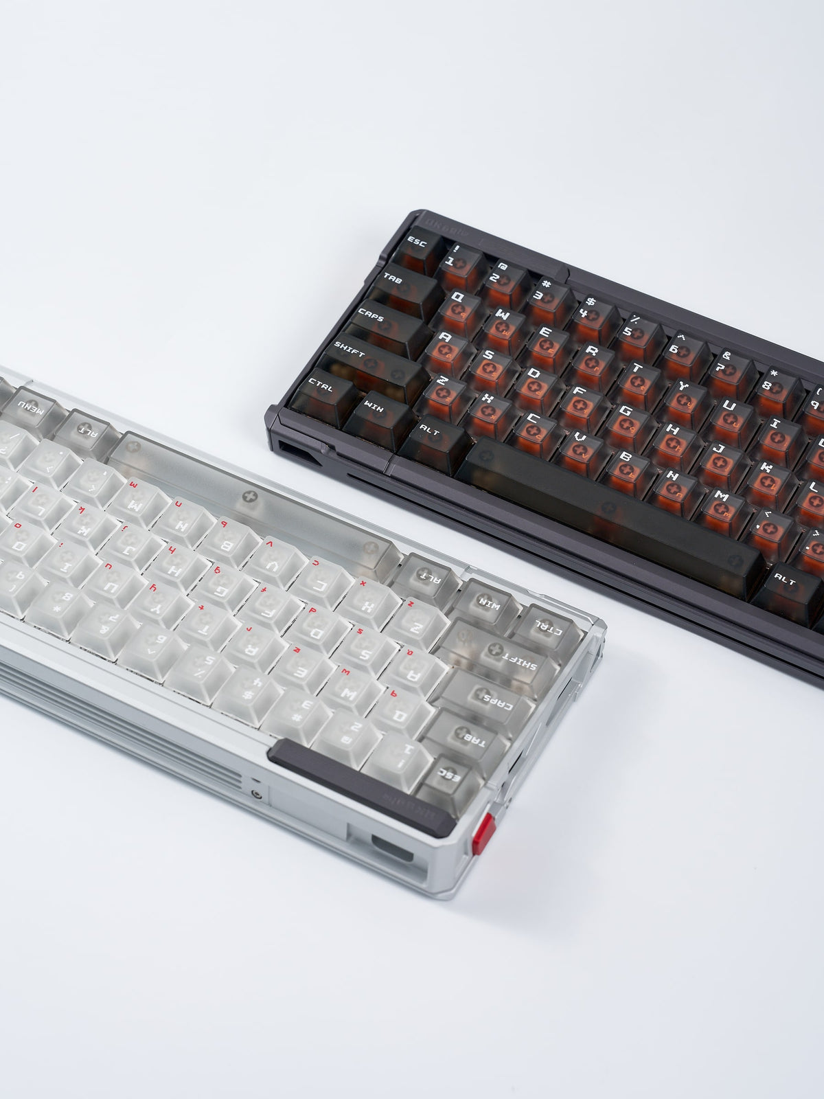 QK60 HE in Aurora Silver und Meteorite Grey nebeneinander, Schrägansicht auf hellgrauem Untergrund